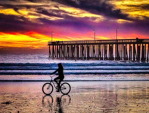 Cyclist on the beach at sunset in Cayucos, California