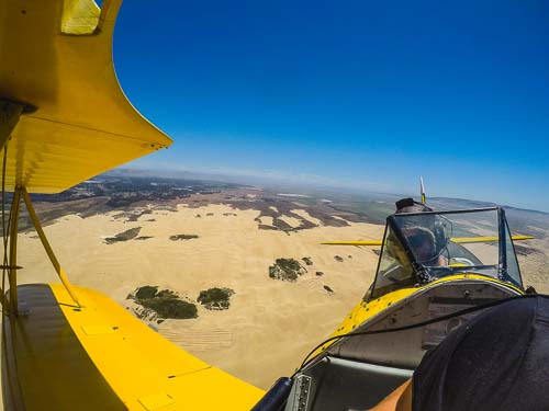 A biplane flies high over Oceano, California