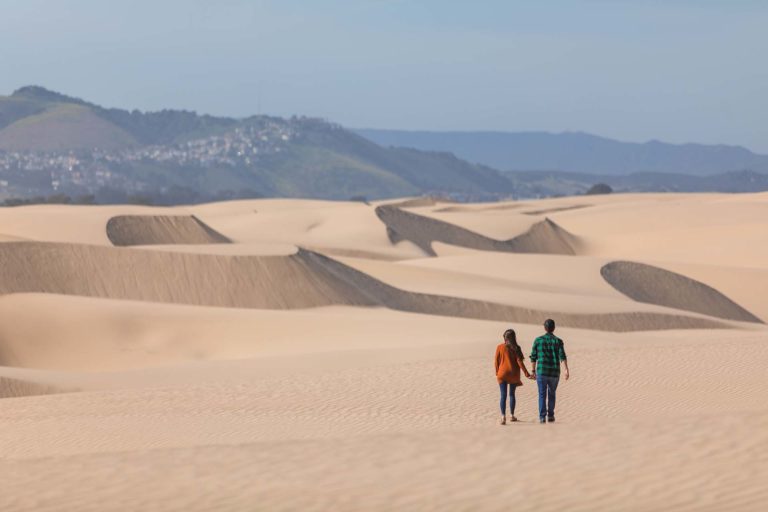 A couple walking on sand dunes at the Oceano Dunes